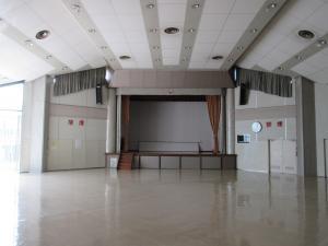 広々とした空間でグレーが基調のホール全体の舞台を正面に写した写真