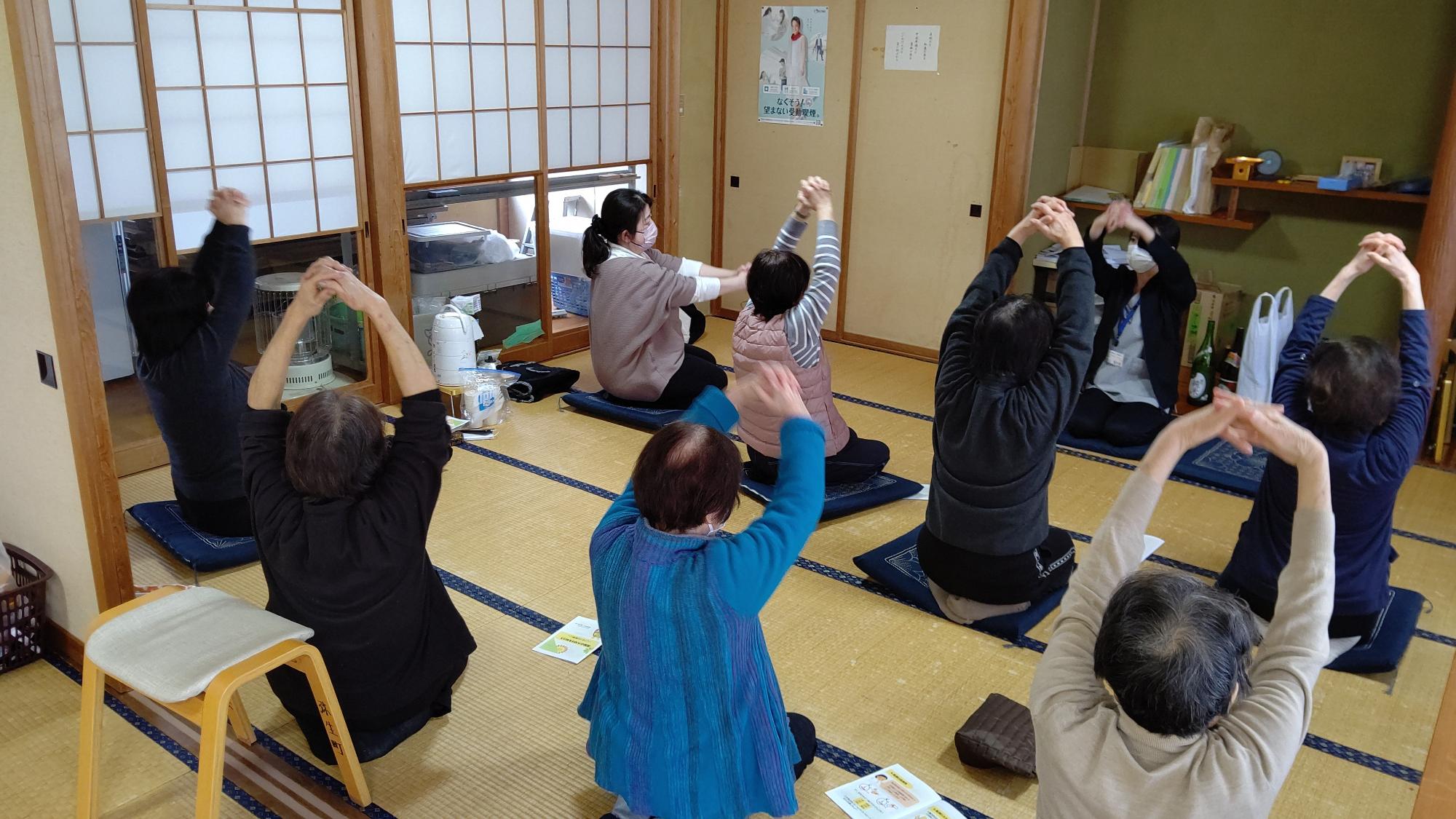 参加者の皆さんが椅子に座って片足を上にあげている写真