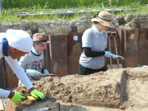 遺跡で発掘調査作業をしているドイツ・チュービンゲン大学から2名の留学生と1人の男性の写真