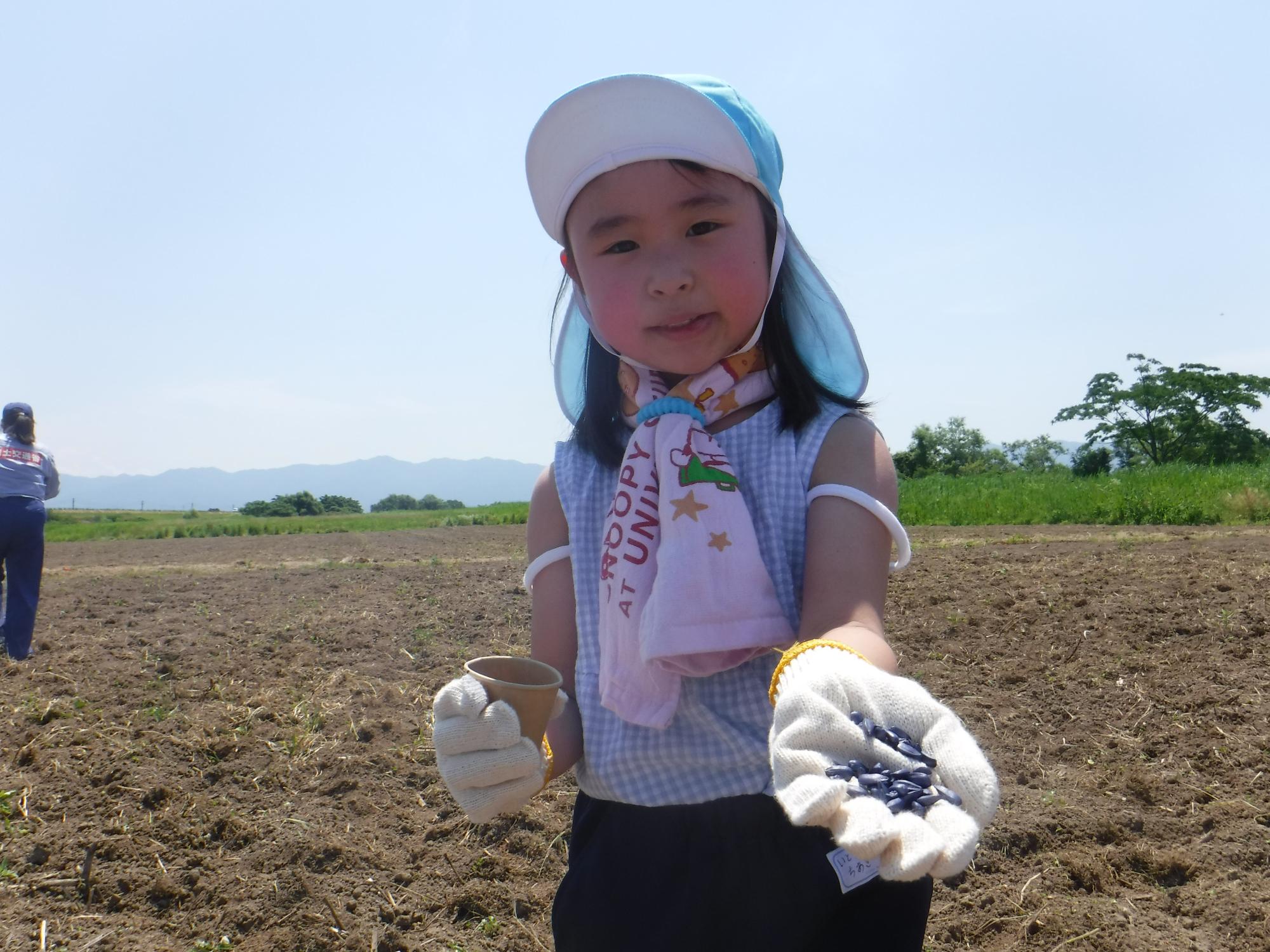 子ども達が一生懸命撒いているひまわりの種をカメラに向けている様子