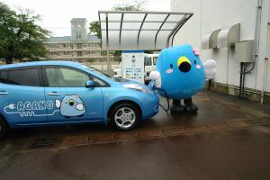 急速充電をしている水色の車と阿賀野市キャラクター「ごずっちょ」の写真