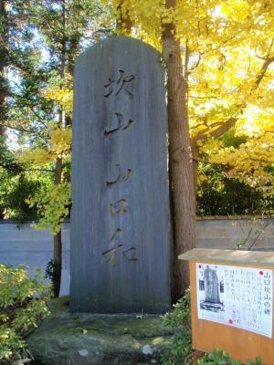 鮮やかな黄色の木々と山口和の石碑が建っている写真