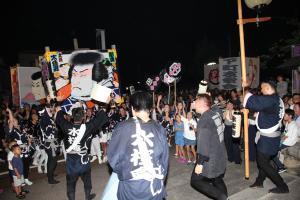 ブルーの法被を着た人々が五右衛門の絵を持ち市民達と一緒に来舞をしている写真