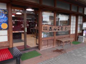 入り口に赤黒の椅子と木製の椅子が置いてある「おんこ茶屋」の外観写真