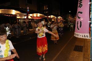 赤と緑の着物を着た女性達が路上で民踊流しを踊っている写真