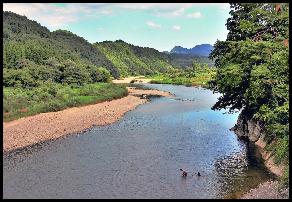 川で遊ぶ人を写した穏やかな山河の写真