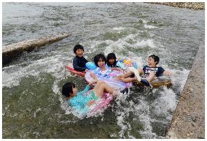 浮き輪で川遊びを楽しむ子どもたちを写した写真