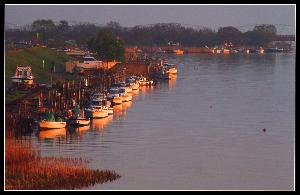 川に停泊している舟が朝日を浴びている写真
