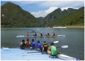 川岸に接岸しているボートに乗っているチームと川で練習をしているチームの写真