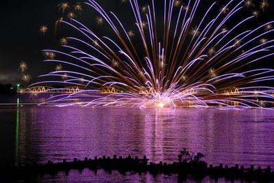 水中花火の光が反射して水面が紫色に光っている阿賀野川の写真