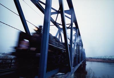 川にかかった鉄橋を走り抜けていくSLの写真
