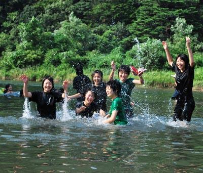 川の中で水しぶきを挙げてはしゃいでいる様子の女子生徒たちの写真