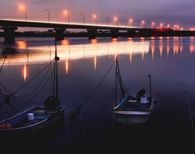 2艘のボートと阿賀野川にかかる橋の街灯に等間隔に明かりが灯っている写真