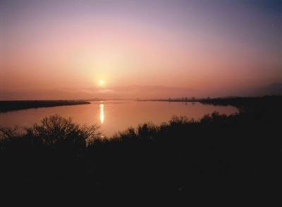 地平線から昇る太陽とオレンジ色に輝く空と川の写真