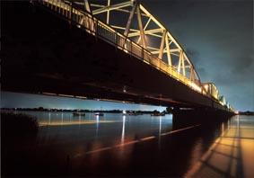 光が反射して暗闇の中で黄色く浮かび上がる鉄橋の写真