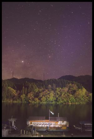 紫色の夜空に輝く無数の星と阿賀野川の川岸に停まっている船の写真