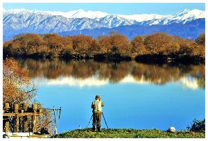 秋の澄み切った山々が水面に映る様子をカメラマンが撮影している写真