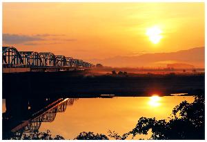 朝日に照らされた川面と橋を写した写真