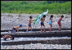 川辺で子供たちが遊んでいる写真