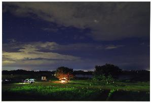 夜に土手でキャンプを楽しんでいる様子を遠くから撮影した写真