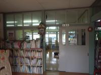 教室のドアが開いており、廊下の隅には本棚にたくさんの本が並べられている写真