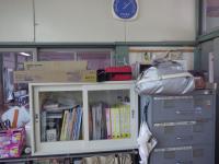 壁側に本や書類などが整理されており、整理棚の上に赤いバック「AED」が置いてある写真