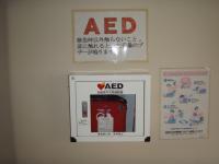 AEDの設置場所に貼られた使用方法と赤いAEDの写真