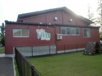 木造で作られた建物の壁に「わくわくHills」と書かれており、その建物前には緑色の芝生が植えられている写真