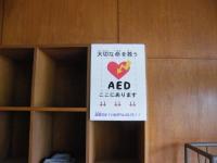 茶色の棚に「AED」と書かれた紙が貼ってある写真