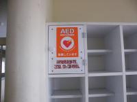 壁に棚が設置され、棚の左上に「AED」と書かれた扉がある写真