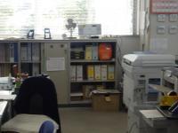 書類などが入っている棚やコピー機デスクや椅子が置いてある事務室内の写真