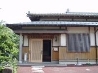 瓦屋根で平屋づくりの建物、空いている玄関の扉と玄関まで続く飛び石の写真