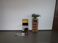 事務所内の壁際に置かれている観葉植物とAEDの機械の写真