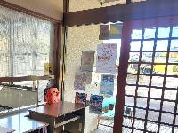 黒いソファが置いてあり、大きなガラス張りの窓がある事務室窓口カウンターの写真