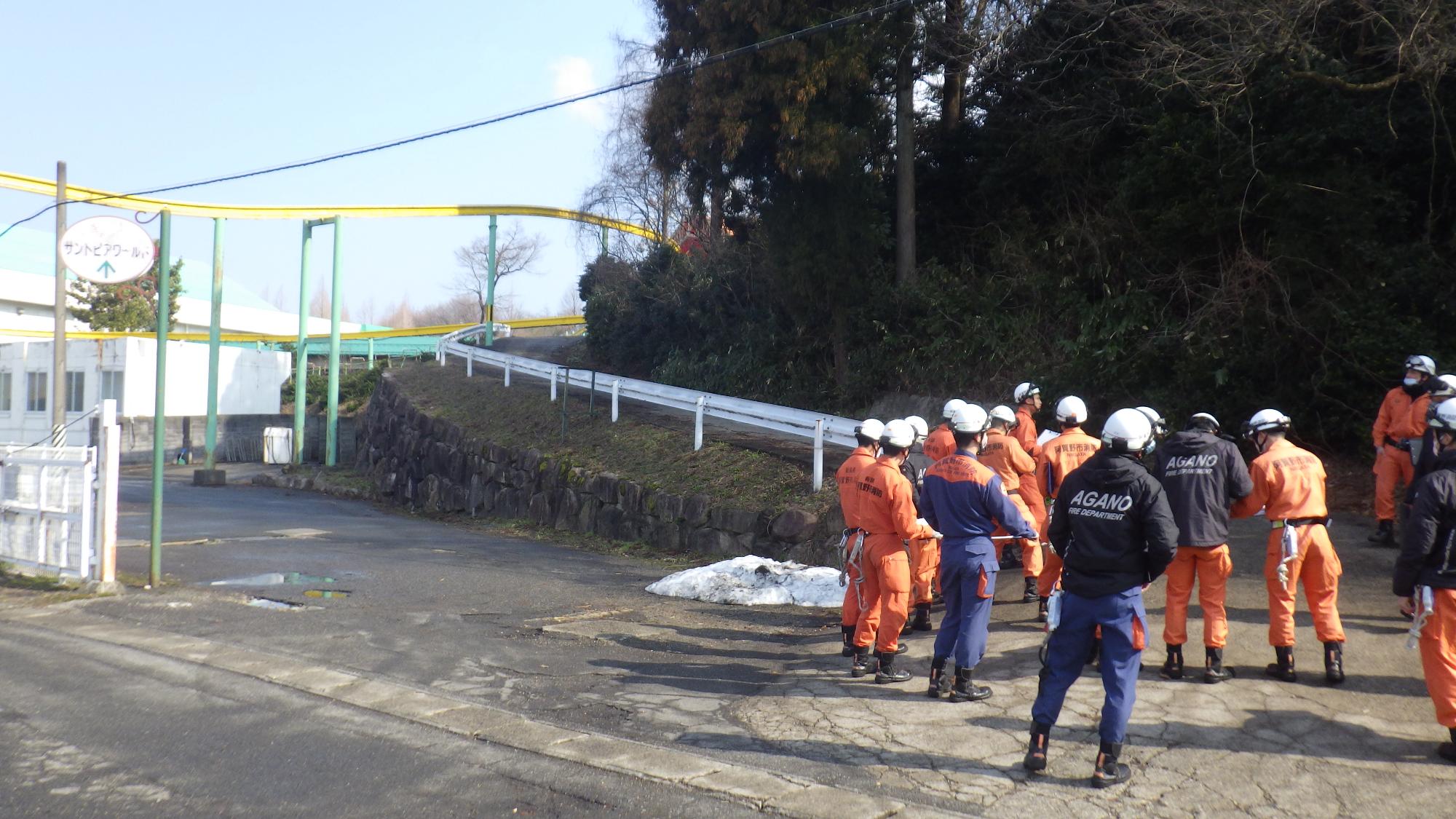 サントピアワールドの屋外で十数名の救助隊員が訓練前に確認の話し合いをしている様子